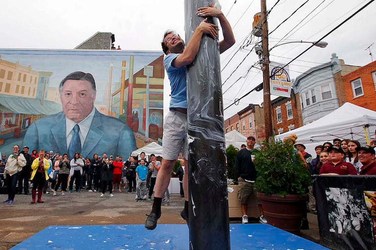 William Harvey attempts to climb the greased pole at the South 9th Street Italian Market Festival on Saturday, May 21, 2016. Harvey is traveling the nation experiencing local cultural community events.