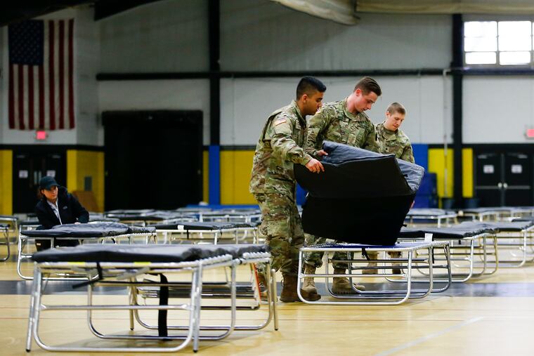 Members of the 103rd Brigade Engineer Battalion National Guard put together cot beds in the gymnasium at the Glen Mills School on Saturday. FEMA and National Guard members will assemble medical equipment and beds in the field hospital to make room for coronavirus patients elsewhere.