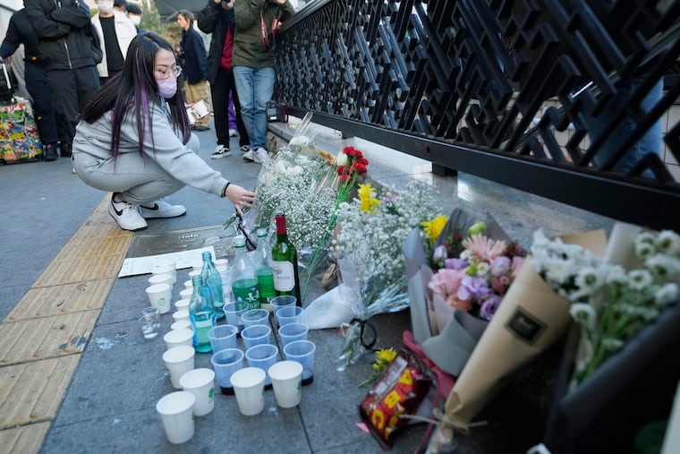 A woman places a bouquet of flowers to pay tribute to victims near the scene of the deadly incident in Seoul, South Korea.