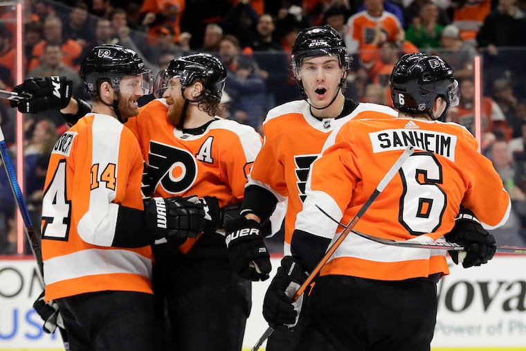 (From left) Flyers center Sean Couturier, right winger Jake Voracek, and defenseman Phil Myers celebrate a goal by defenseman Travis Sanheim in the Flyers' 6-5 shootout win over Boston in January.