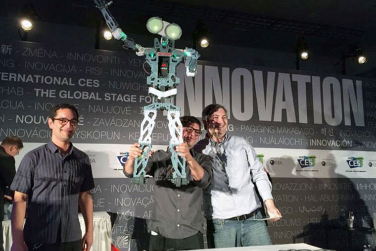 Andres Garza, project designer for the Meccanoid G15 KS, holds the 4-foot robot in triumph after it won the Last Gadget Standing competition at the Consumer Electronics Show. He was joined onstage by his brother and codesigner, Felipe Garza (left), and engineer Chris Hardouin. The Meccanoid, with 64 megabytes of memory and voice recognition, should be available by mid-August.