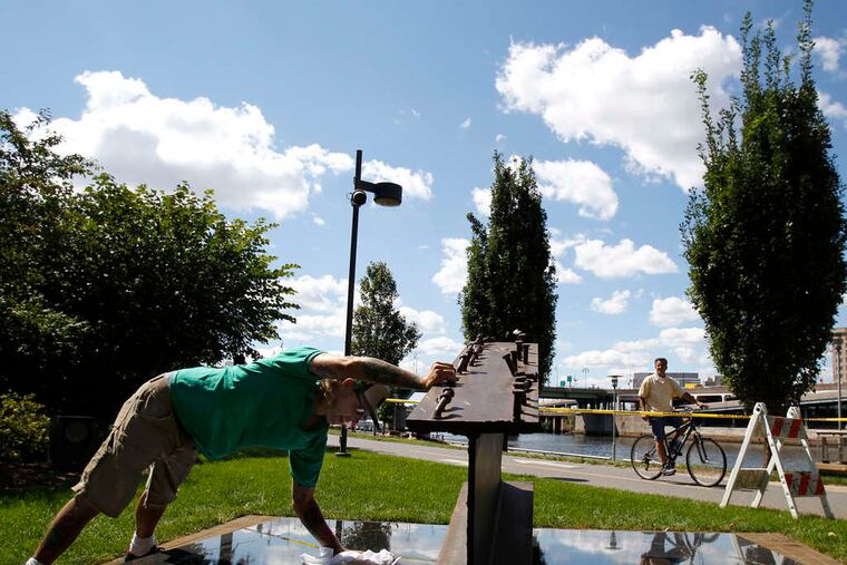 Eric Pauly on the banks of the Schuylkill River cleaning a memorial, which has the names of the three Philadelphia residents who died in the World Trade Center on 9/11.