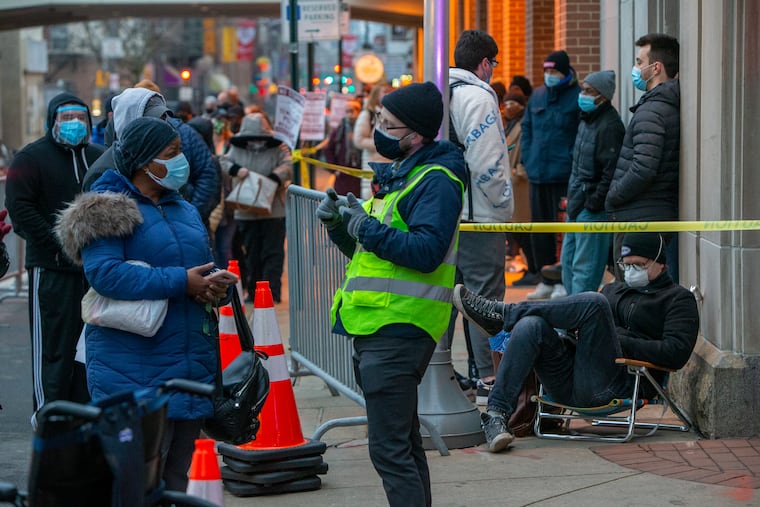People wait at 12th and Race Streets, outside the Pennsylvania Convention Center, Wednesday as the city began accepting walk-ins for vaccination. Residents from 22 under-vaccinated zip codes in the city were able to walk up and wait in line with a vaccine instead of making appointments online.