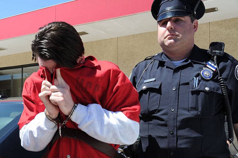 Neil K. Scott, 25, Haverford, covers his face after he was arraigned in Montgomery County Magisterial District Court and charged with allegedly the leader of a drug distribution ring April 21, 2014. The ring sold drugs to local high schools and colleges. ( CLEM MURRAY / Staff Photographer )