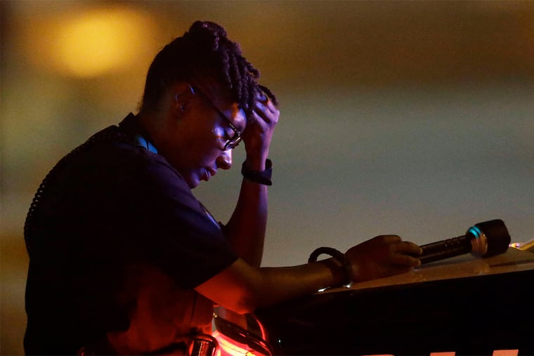 A Dallas police officer pauses in the aftermath of the shooting.