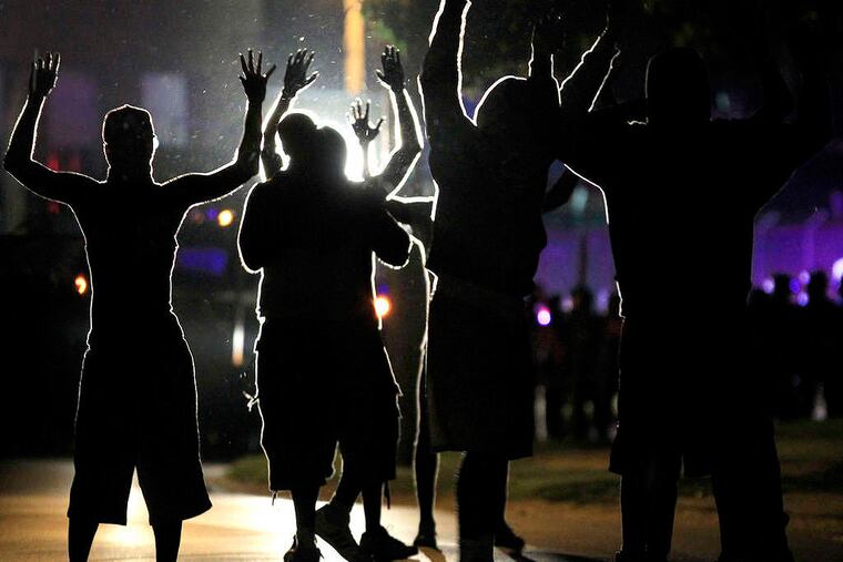 People raise their hands in the middle of the street as police wearing riot gear move toward their position trying to get them to disperse Monday, Aug. 11, 2014, in Ferguson, Mo. The FBI opened an investigation Monday into the death of 18-year-old Michael Brown, who police said was shot multiple times Saturday after being confronted by an officer in Ferguson. Authorities in Ferguson used tear gas and rubber bullets to try to disperse a large crowd Monday night that had gathered at the site of a burned-out convenience store damaged a night earlier, when many businesses in the area were looted. (AP Photo/Jeff Roberson)