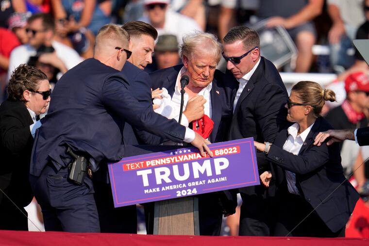 Republican presidential candidate former President Donald Trump is helped off the stage after an assassination attempt at a campaign event in Butler, Pa., on July 13, 2024.