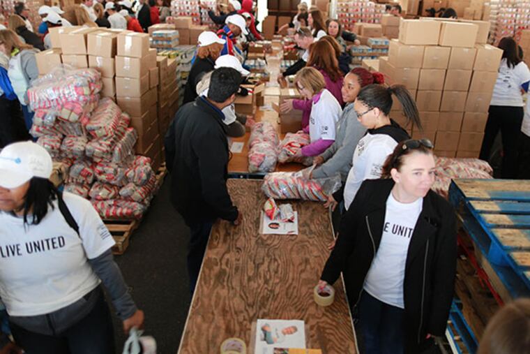 United Way volunteers will pack thousands of meal kits to stock local food pantries throughout the region at Campbell Field in Camden Wednesday, April 9, 2014. ( DAVID SWANSON / Staff Photographer )