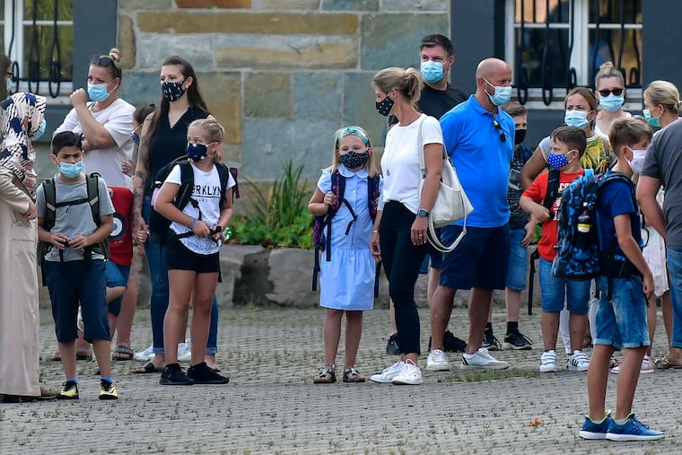 Parents wait with children in a schoolyard in Gelsenkirchen, Germany on Aug. 12, the first day of school there.