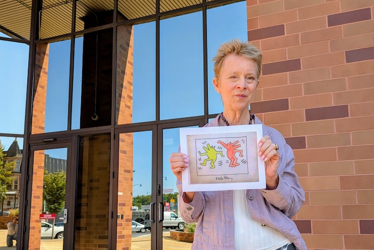 Christine Oaklander poses outside the federal courthouse in Reading holding a scan of a fake Keith Haring artwork fraudulently sold to her by Carter Reese.