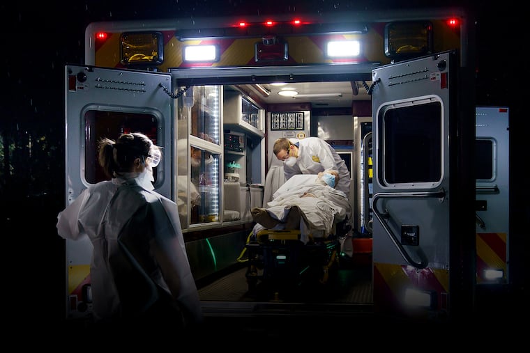 EMT Sarah Awad, left, and paramedic David Goroff, right, from Narberth Ambulance, care for a man in his 60s, a resident in a nursing care facility in Bryn Mawr.