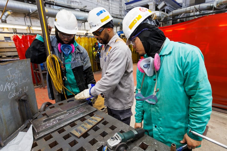 Instructor John Williams (center) explains how to prepare a 3G groove plate on a shop table to apprentices Justin Felin (left) and Aaron Le at the Hanwha Philly Shipyard Training Academy Apprentice Program last summer at the former Navy Yard in South Philadelphia.