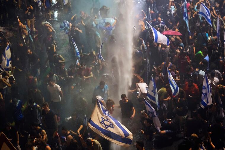 Riot police tries to clear demonstrators with a water canon during a protest against plans by Netanyahu's government to overhaul the judicial system, in Tel Aviv, Monday, July 24, 2023. (AP Photo/Oded Balilty)