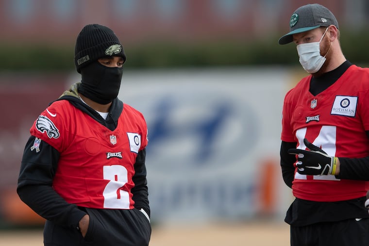 Carson Wentz (right) advises his apparent successor, Jalen Hurts, during a chilly Wednesday practice.