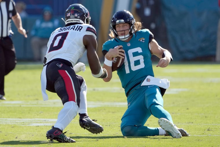 Jaguars quarterback Trevor Lawrence slides in front of Texans linebacker Azeez Al-Shaair on Sunday. Lawrence was injured on the play.