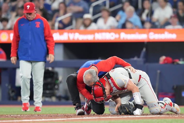 Phillies catcher J.T. Realmuto is checked on after being hit by a foul ball in the ninth inning against the Blue Jays on Wednesday.