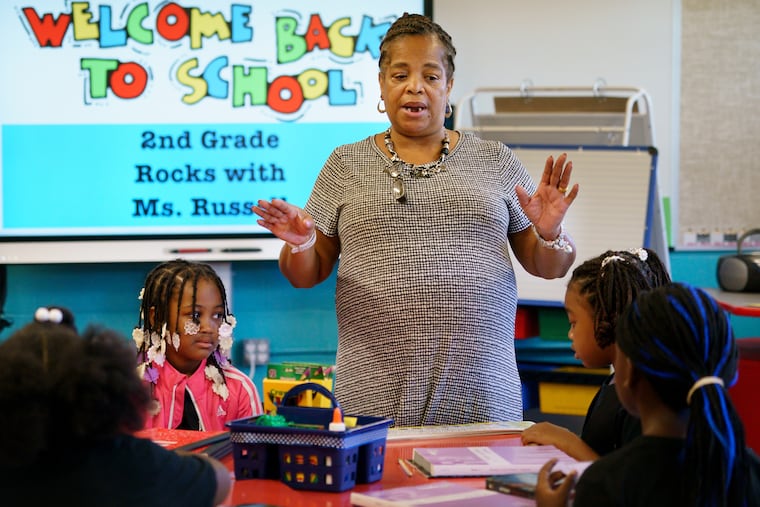 Second-grade Teacher Deborah Russell, center, instructs students Lilly Jane Johnson-Russell, left, and Jasmine Bryant, right, on the first day of school at Robert Morris Elementary in North Philadelphia on Sept. 3, 2019.