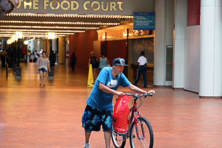 A pedestrian walks his bike through the Gallery mall. (Michael Bryant/Staff Photographer)