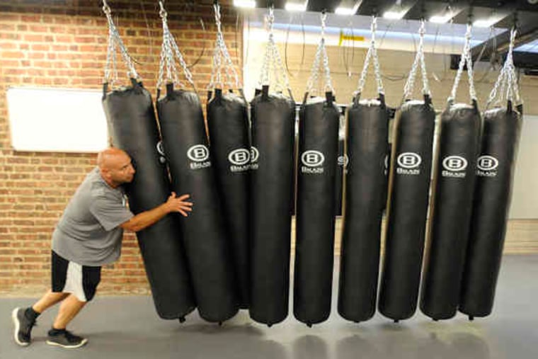 Strength and conditioning coordinator Jim Steel pushes heavy bags out of the way to make room for cardiovascular training. The new facility has sections for athletic training and for recreational fitness, the latter open to students, faculty, staff, and alumni.