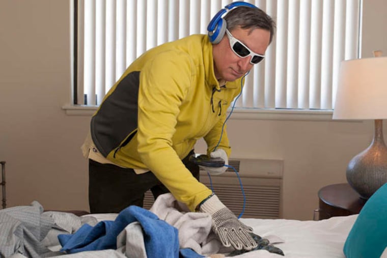 Richard Abraham, whose mother lives at the Watermark, attempts routine household chores with thick gloves, blinding glasses, and disorienting noise.