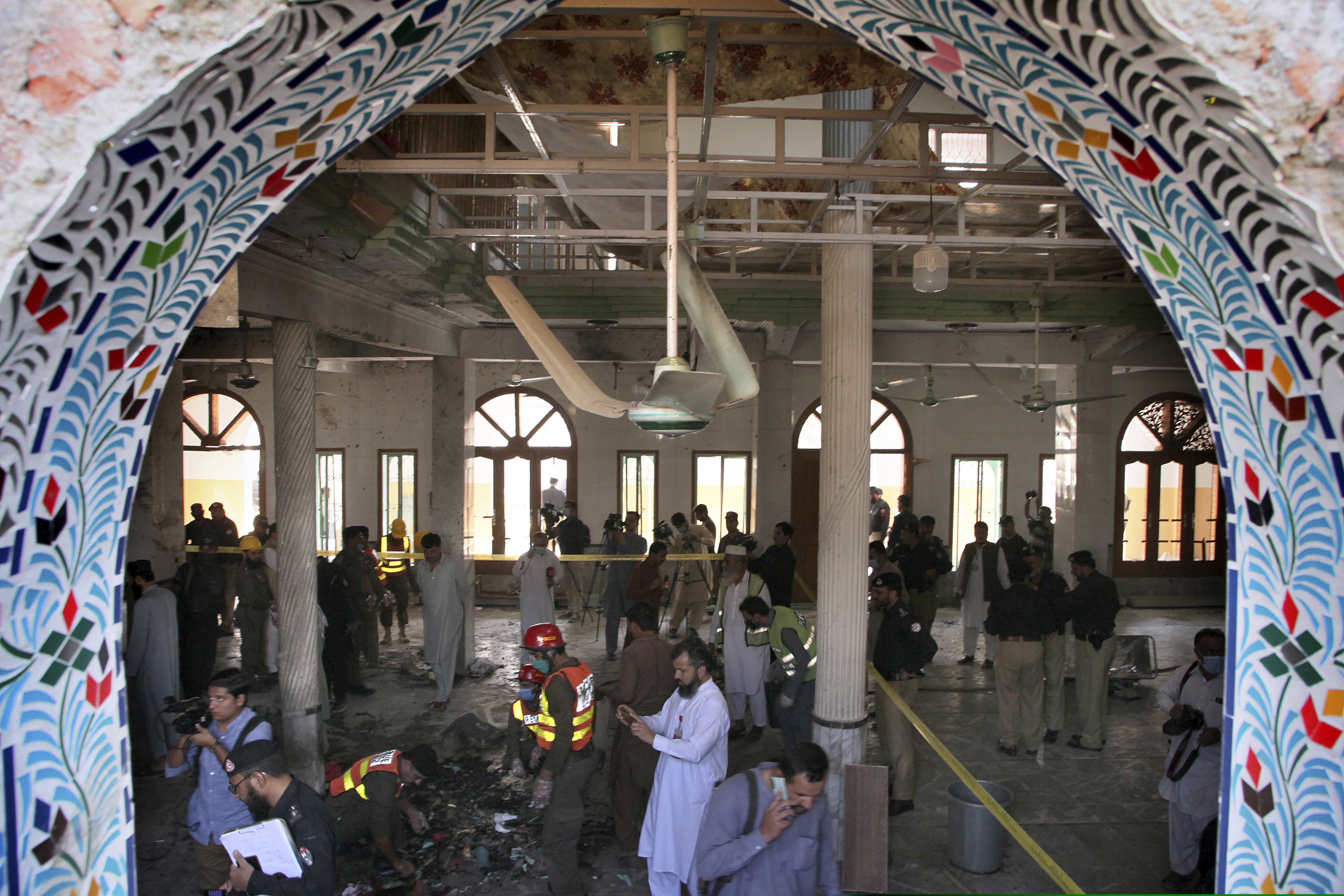 Pakistani rescue workers and police officers examine the site of a bomb explosion in an Islamic seminary, in Peshawar, Pakistan, on Tuesday.