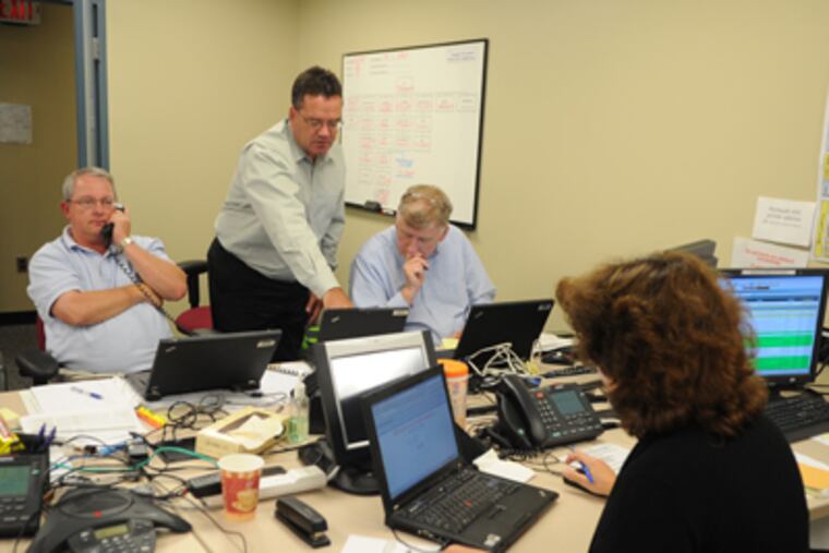From left, Phil Eastman, John McDonald and John Golden manage PECO teams working in the field to restore power inside PECO's Emergency Operations Center in Plymouth Meeting on Monday. (Sarah J. Glover / Staff Photographer)