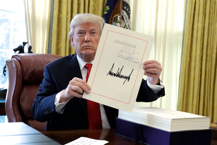 President Donald Trump displays the Tax Cuts and Jobs Act he signed in the Oval Office of the White House in Washington in 2017. Nearly all of its provisions expire at the end of 2025.