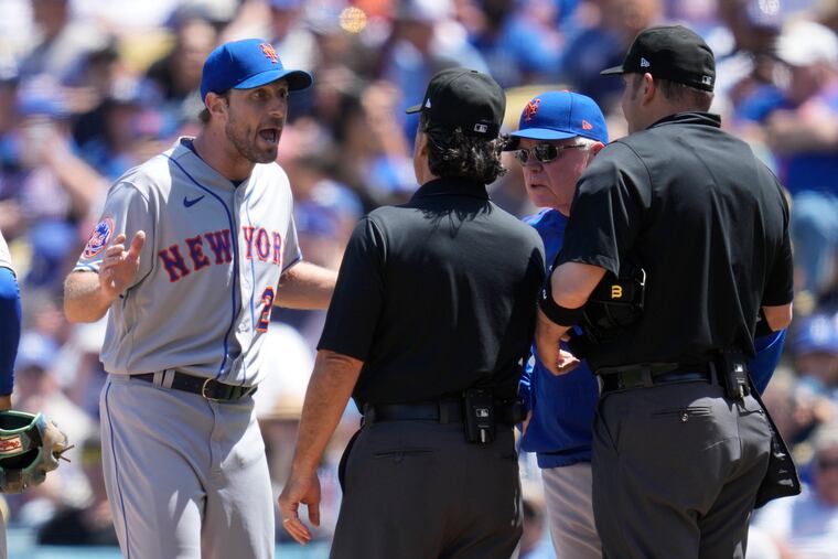 Mets pitcher Max Scherzer and manager Buck Showalter dispute a call from umpire Phil Cuzzi, center, and umpire Dan Bellino, right, after they found a problem with Scherzer's glove during the fourth inning.