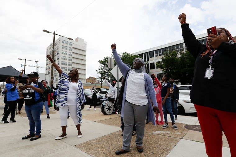 Demonstrators raise their fists at the end of a rally in opposition to the closing of Black-led charters at the School District of Philadelphia Headquarters on Thursday, June 23, 2022.