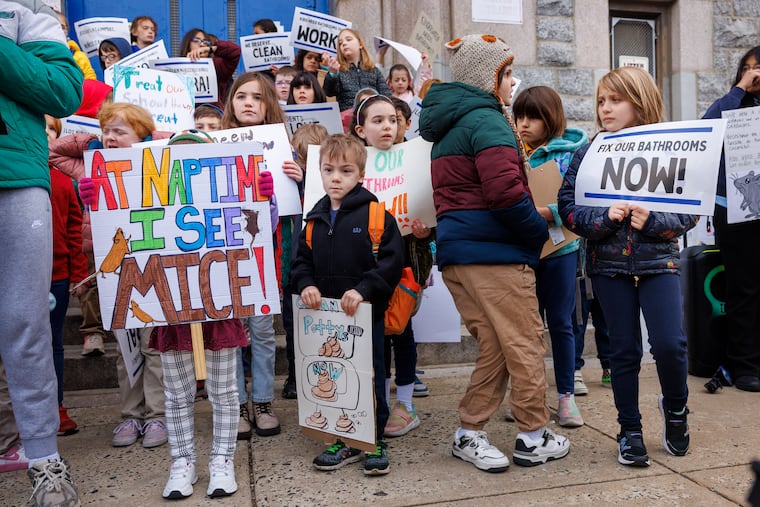 Students with signs gather together to protest outside Southwark Elementary school last week. They spoke out about mice, cockroaches, and bathroom problems.