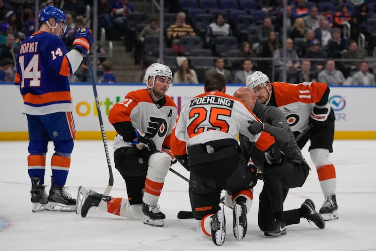 Scott Laughton and Travis Konecny (right) check on Ryan Poehling after Poehling took an illegal check to the head by Islanders’ Max Tsyplakov on Thursday night.