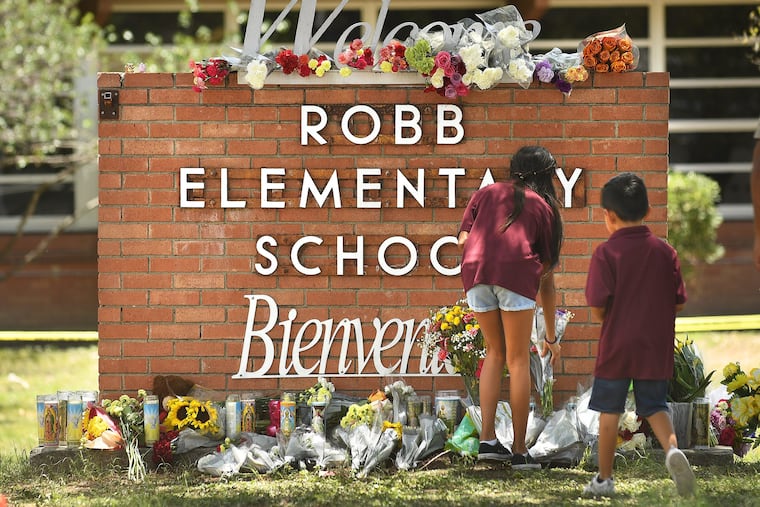 Family members who lost a sibling place flowers outside Robb Elementary School in Uvalde, Texas. (Wally Skalij/Los Angeles Times/TNS)