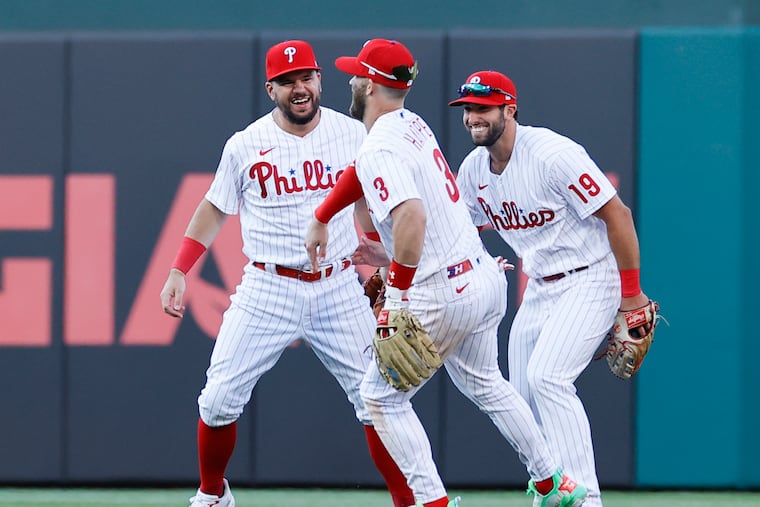 Phillies outfielders Kyle Schwarber, Bryce Harper and Matt Vierling celebrate their 9-5 opening-day win over the Athletics on Friday.
