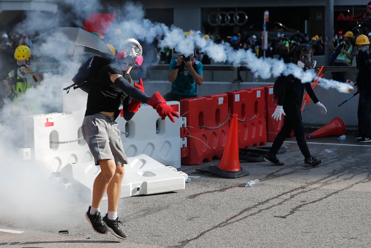 A protester throws back a tear gas canister in Hong Kong on Monday, Aug. 5, 2019. Droves of protesters filled public parks and squares in several Hong Kong districts on Monday in a general strike staged on a weekday to draw more attention to their demands that the semi-autonomous Chinese city's leader resign.