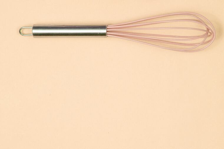 Silicone kitchen whisk, tray of chicken eggs on yellow background. Cooking concept, Top view, flat lay, minimalism.