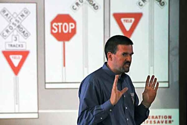 SEPTA director of system safety, Scott Sauer stands in front of a slide on a screen and talks about the passive signs that the students might see around a railroad crossing and what they all mean. SEPTA director of system safety, Scott Sauer gives a safety talk at the Nazareth Academy Grade School trying to reduce a growing death toll on SEPTA rails. 500 transit employees and volunteers will swarm local rail stations and bus stops on Wednesday to warn people to stay off the tracks. “Any time is train time,” 04/30/2013 ( MICHAEL BRYANT / Staff Photographer )