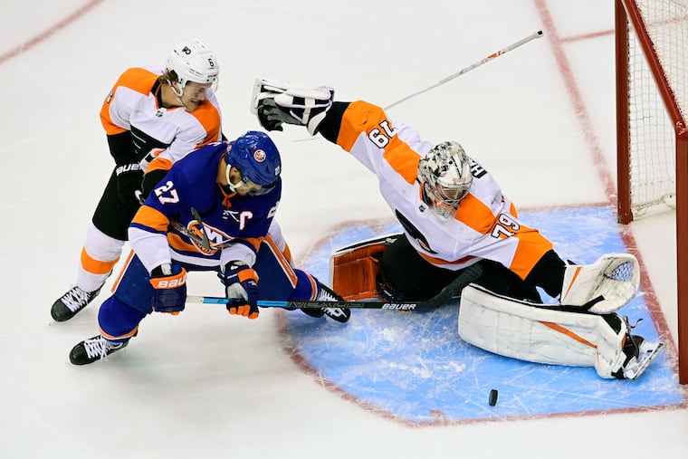 Flyers goaltender Carter Hart (right) stops Islanders left wing Anders Lee during overtime of the Flyers' 5-4 victory Thursday night.