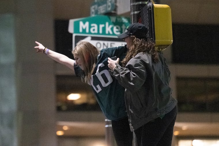 Philadelphia Eagles climb up poles to celebrate the NFC championship win over the Washington Commanders on Sunday.
