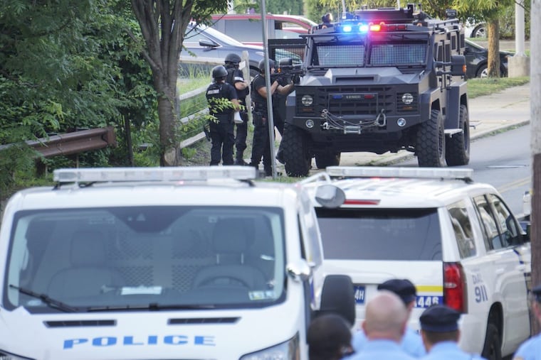 Philadelphia Police SWAT unit officers behind an armored vehicle with weapons drawn during a standoff with barricaded suspect on E. Haines in the E. Germantown section of Philadelphia, Tuesday.