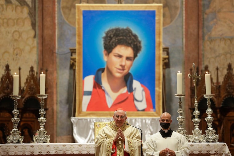 An image of 15-year-old Carlo Acutis, an Italian boy who died in 2006 of leukemia, is seen during his beatification ceremony celebrated by Cardinal Agostino Vallini, center, in the St. Francis Basilica, in Assisi, Italy.