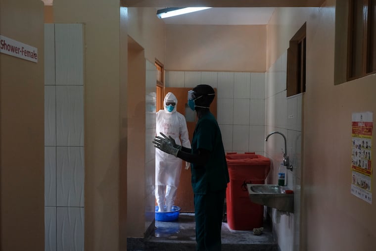 Doctors disinfect themselves after visiting a patient who was in contact with an Ebola victim, in the isolation section of Entebbe Regional Referral Hospital in Entebbe, Uganda Thursday, Oct. 20, 2022. Uganda's Ebola outbreak is "rapidly evolving" a month after the disease was reported in the country, a top World Health Organization official said Thursday, describing a difficult situation for health workers on the ground.