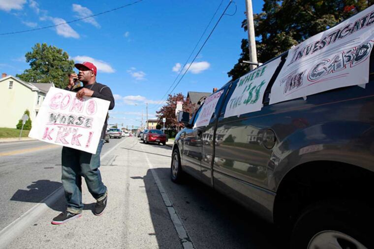 Ron Suber, who has nephews in the district, protesting Monday with signs about the school officials involved in the texts. ( DAVID SWANSON / Staff Photographer )