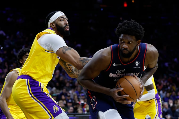 Sixers center Joel Embiid holds the basketball defended by Los Angeles Lakers forward Anthony Davis on Monday, November 27, 2023 in Philadelphia.