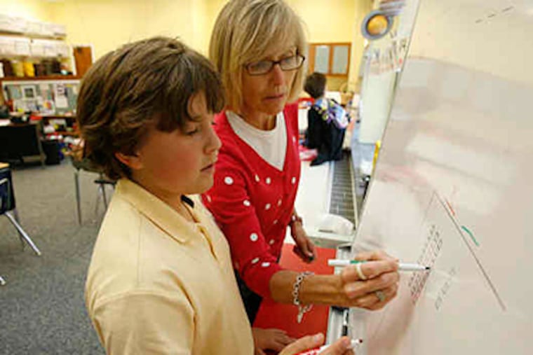 Stratford Friends School teacher Debbie Koutsiouroubas works with Jack Benoliel. While "other programs jump to abstract quickly," she said, she tries to give students a picture of math basics. (Charles Fox / Staff)