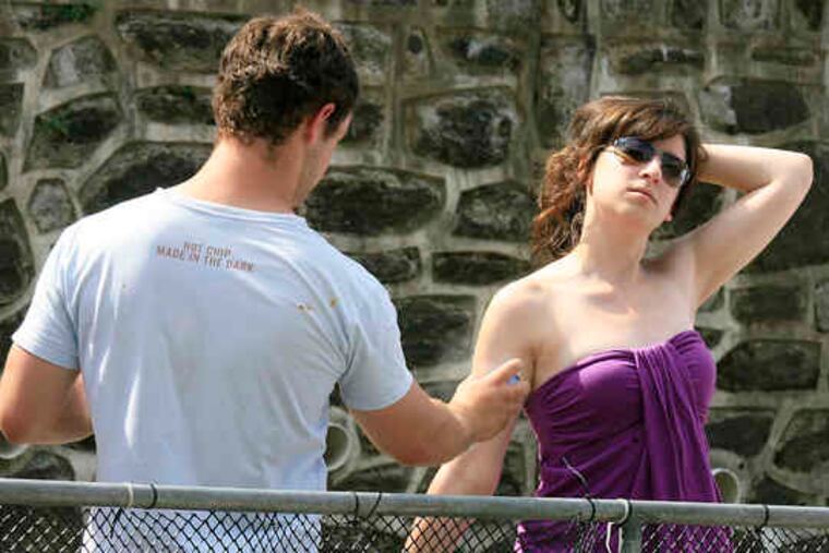 STEVE WAYE, 22, of Center City, sprays sunscreen on friend Sara Gold, 23, of Westchester County, N.Y., while awaiting racers to arrive at the Manayunk Wall during yesterday's Philadelphia International Championship pro cycling race. Story, Page 7.