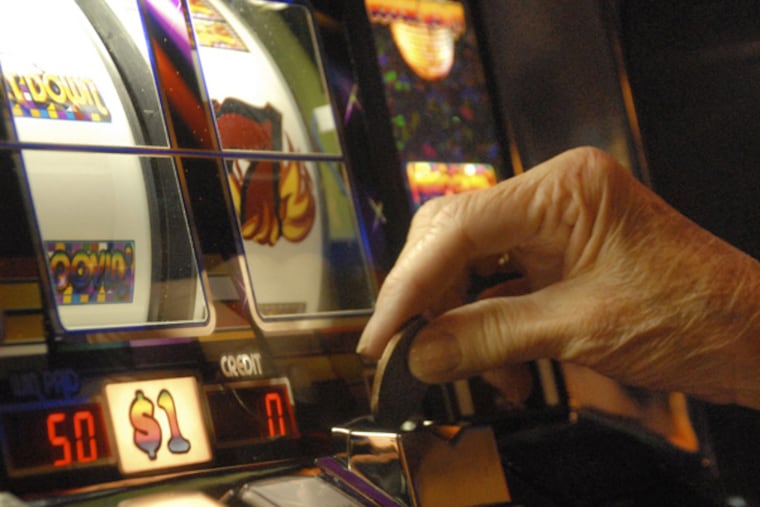 A player puts a dollar coin in a slot machine. (AP Photo/Curt Hudson)
