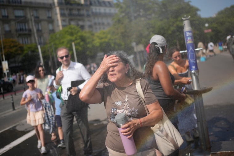 Tourists cool off at a public water fountain in Paris on June 26.