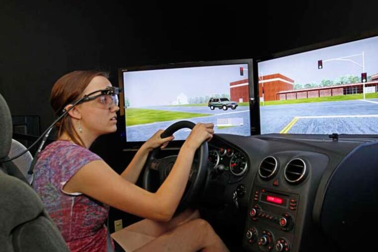 The author, wearing eye-tracking goggles, "drives'' the three-screen simulator as CHOP researchers monitor her to assess her skill.