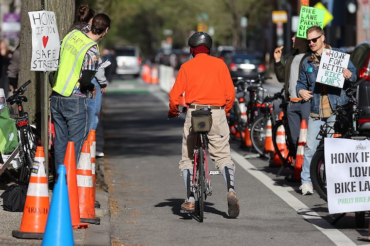 A cyclist pauses in a bike lane to talk with a group protesting near the Tenth Presbyterian Church in Philadelphia, Pa. on Sunday, April 14, 2024. Over the past year, the conversation to expand bike lanes has intensified. In January 2025, Councilmember Young Jr. introduced bills to add bike lanes to three high-traffic streets in Philadelphia.