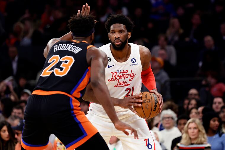 Sixers center Joel Embiid looks to pass around New York Knicks center Mitchell Robinson during the Sixers' win on Christmas Day.
